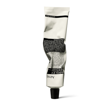 A front view of Parsley Seed Facial Cleansing Masque in an alabaster and black aluminium tube, gently crumpled from application.