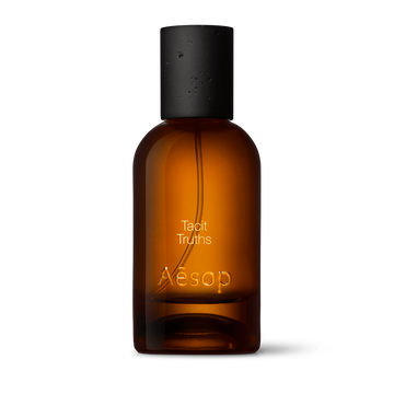 Bernsteinfarbene Flasche des Aesop Tacit Truths Eau de Parfum aus Glas mit schwarzem Verschluss vor weißem Hintergrund.