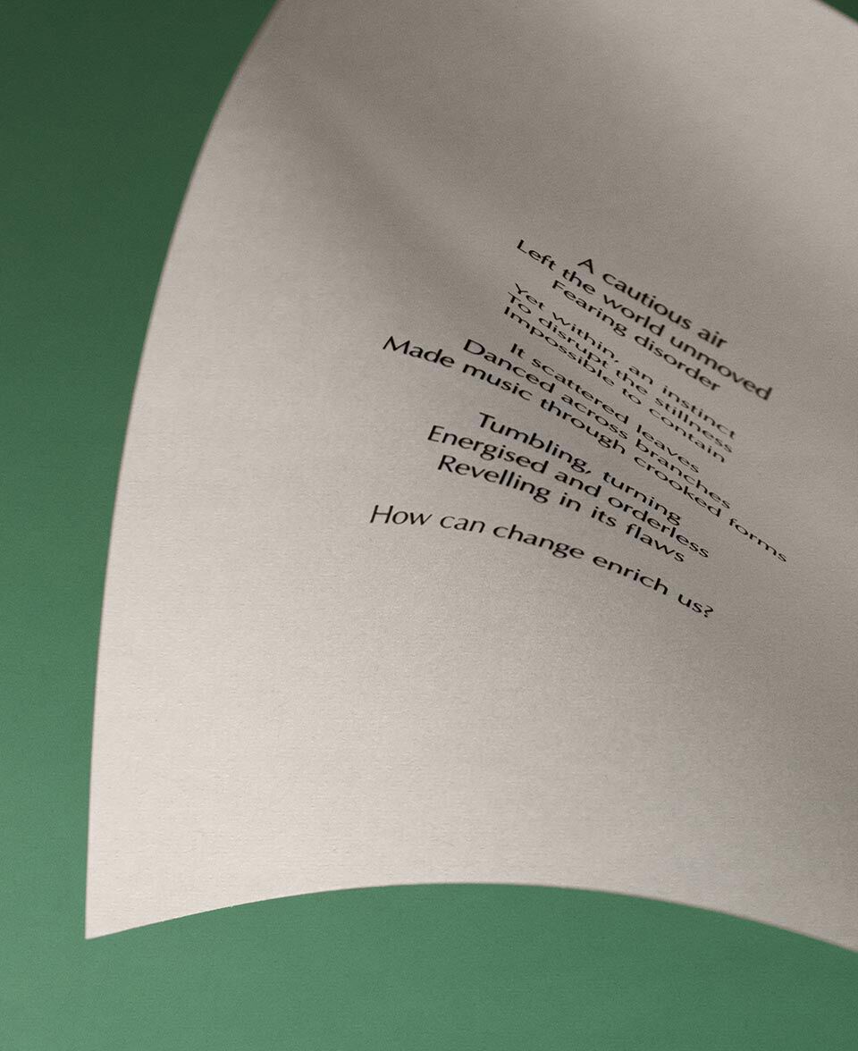 Gebogenes, cremefarbenes Papier mit Gedichttext vor gedampft grunem Hintergrund.