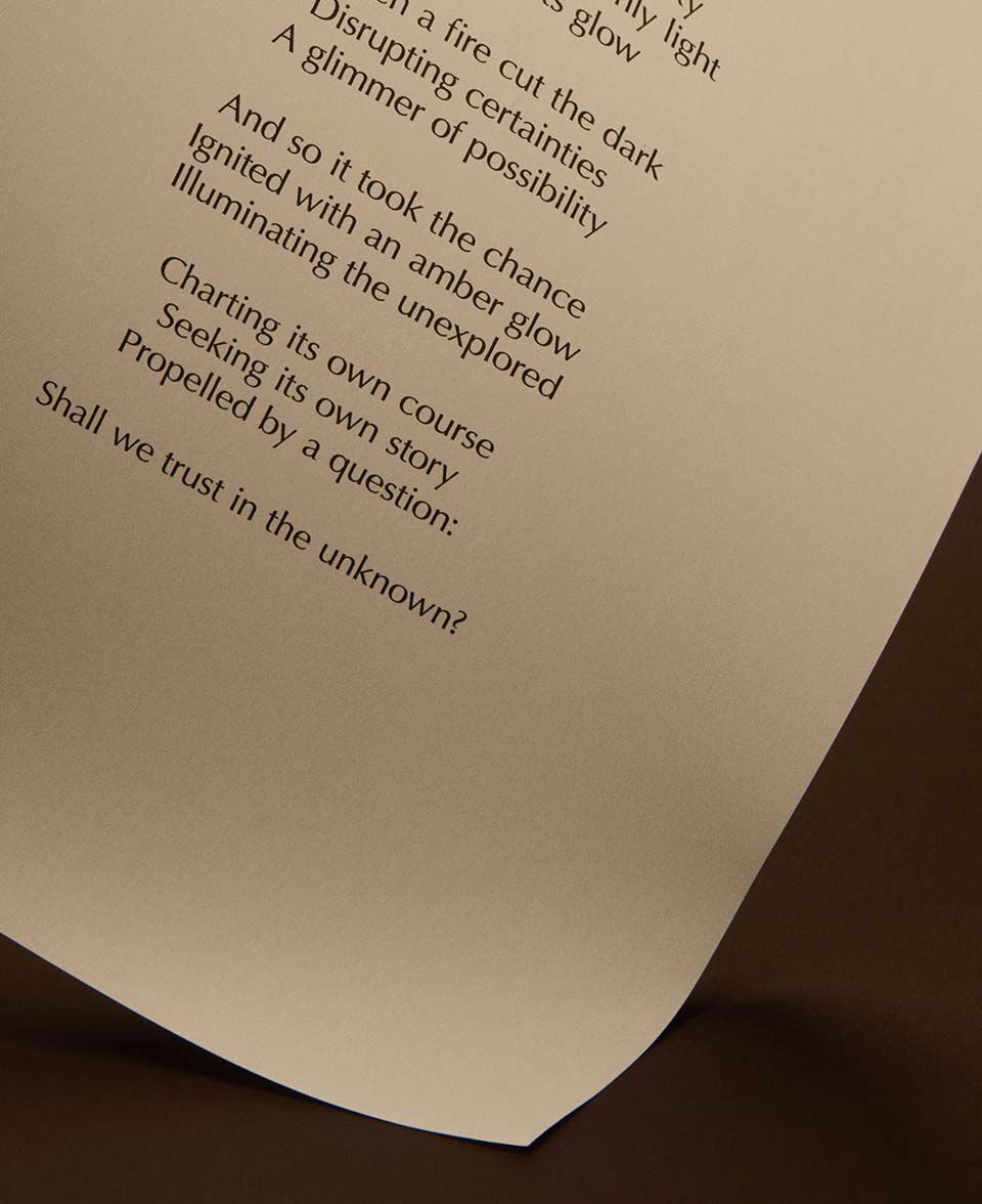 Gebogene Seite mit gedrucktem Gedichttext vor warmem dunkelbraunem Hintergrund.